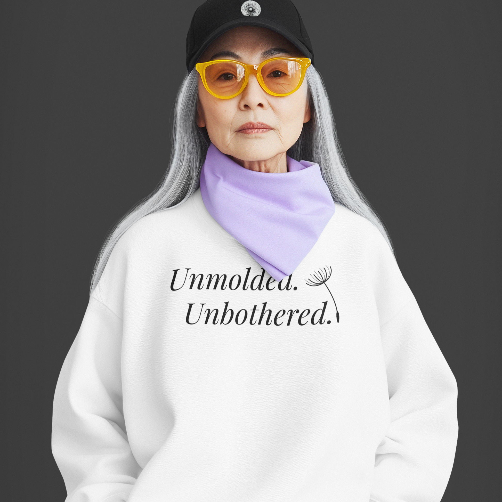 Person with long gray hair wearing a white hoodie with bold front text, yellow sunglasses, and a black cap on a dark background