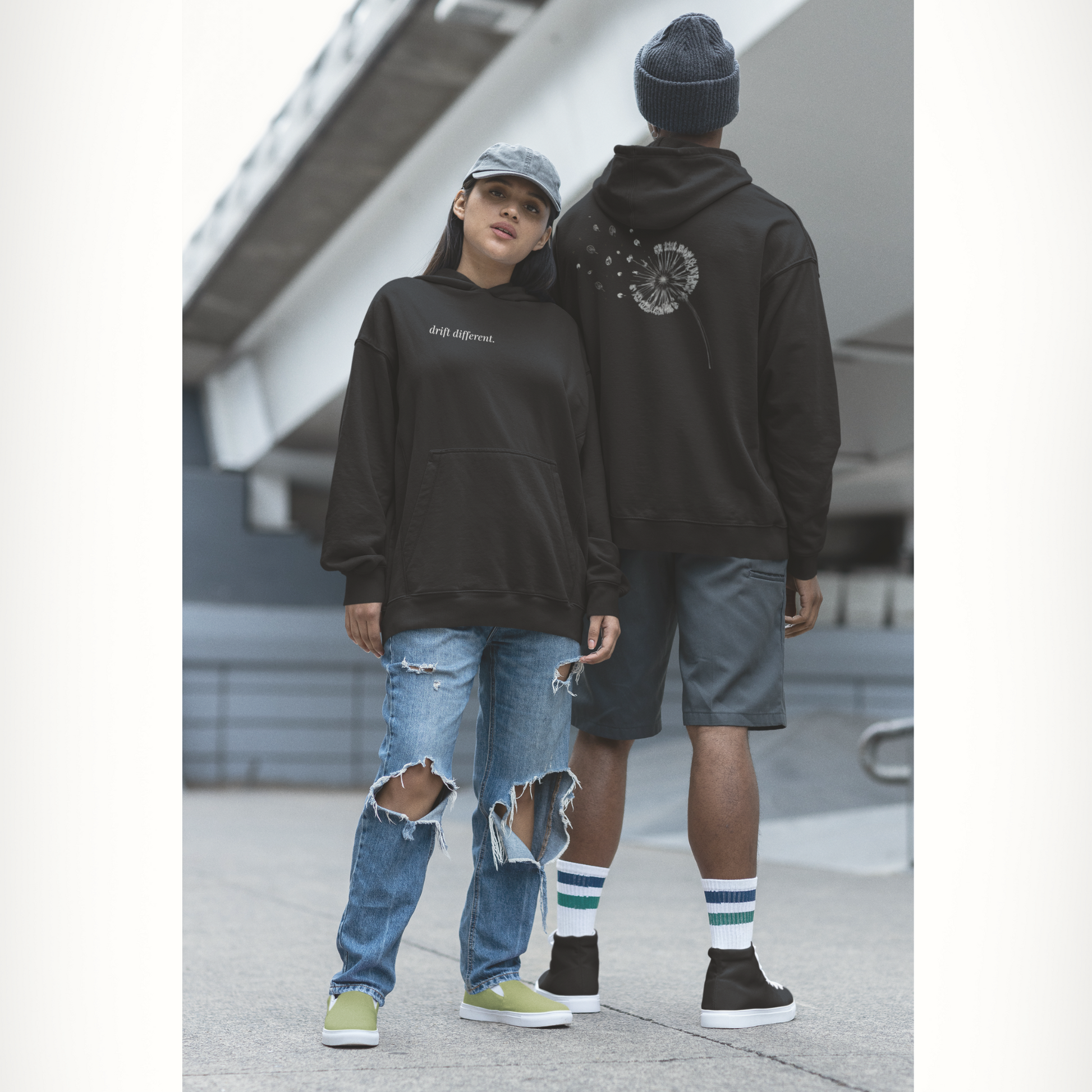 Two people wearing black drift different. hoodies; one font facing and the back of the other with visible branding, standing outdoors.