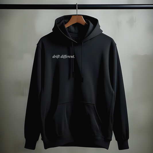 Black drift different. hoodie with minimalist chest print on a wooden hanger against a neutral background